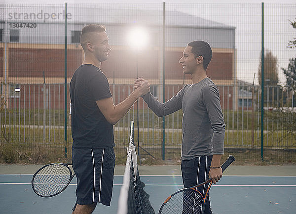Seitenansicht von Freunden  die beim Badminton-Spielen Händchen halten