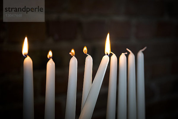 Nahaufnahme von angezündeten Kerzen in der Dunkelkammer gegen eine Ziegelmauer während Chanukka