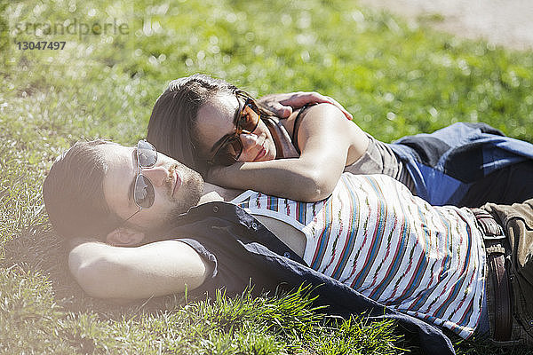 Romantisches Paar liegt im Sommer auf Gras