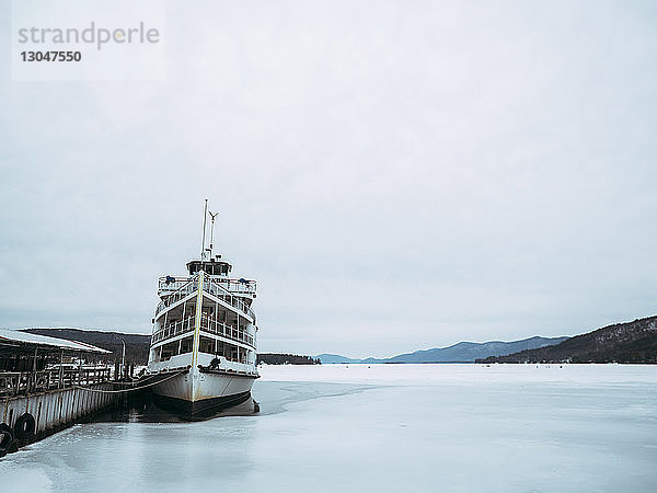 Boot im Hafen auf dem zugefrorenen George-See vor bewölktem Himmel vertäut