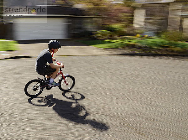 Verschwommene Bewegung eines Jungen beim Fahrradfahren auf der Straße