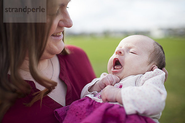 Nahaufnahme einer lächelnden Mutter  die ihre Tochter mit offenem Mund im Park ansieht