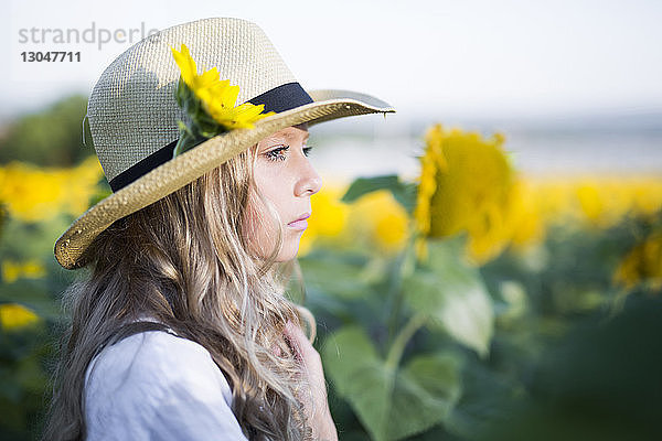 Seitenansicht des nachdenklichen Cowgirls im Sonnenblumenfeld