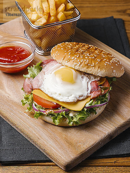 Nahaufnahme von Burger mit Pommes Frites und Ketchup auf Holzschneidebrett serviert