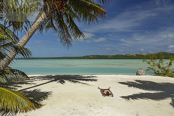 Mann entspannt sich auf Sand am Strand gegen den Himmel