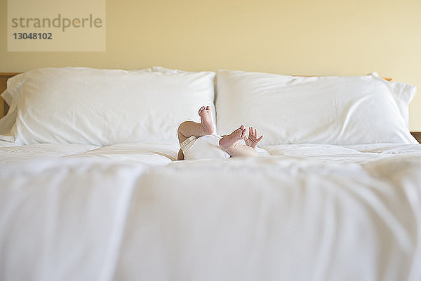 Niedriger Querschnitt eines zu Hause auf dem Bett liegenden Jungen