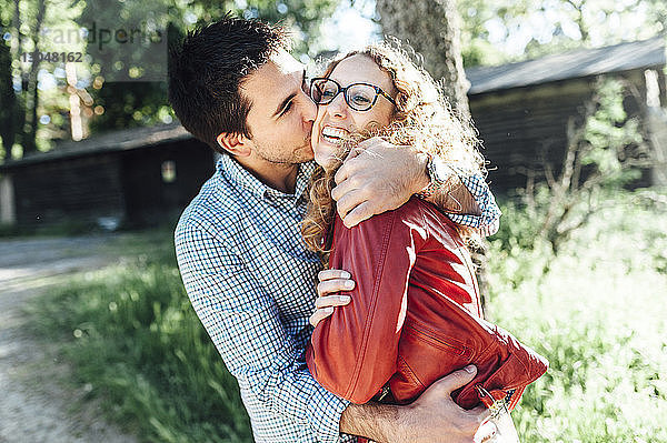 Mann küsst fröhliche Freundin  während er im Hinterhof steht
