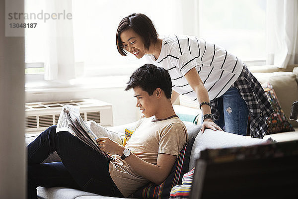 Glückliches Paar liest Zeitung im Wohnzimmer