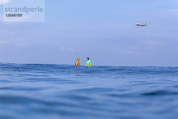 Freunde schwimmen im Meer gegen den blauen Himmel