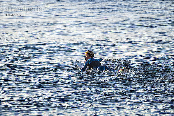 Junger Mann schaut beim Surfen auf See weg