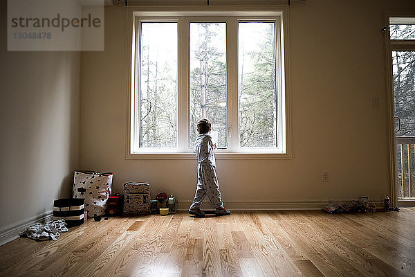 Junge in voller Länge zu Hause am Fenster stehend