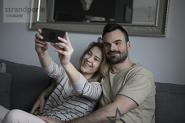 Glückliches Paar  das zu Hause auf dem Sofa sitzt