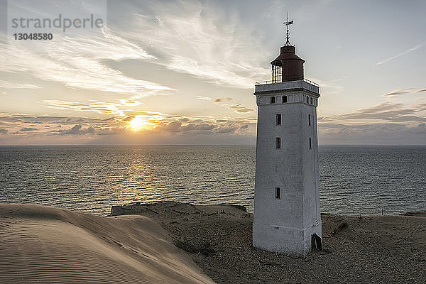 Leuchtturm am Strand gegen den Himmel bei Sonnenuntergang