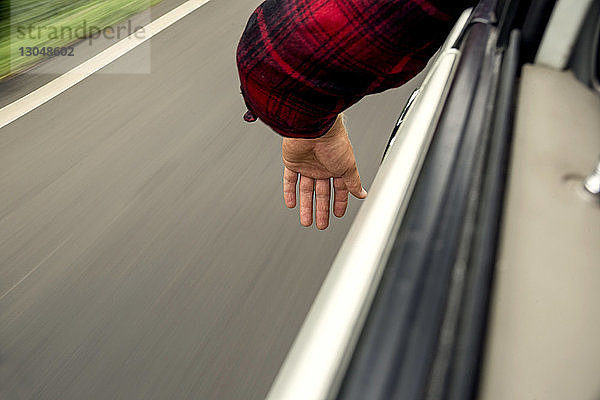 Ausgeschnittenes Bild einer Hand durch ein Autofenster gesehen