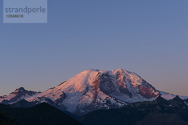Szenenansicht eines schneebedeckten Berges vor klarem blauen Himmel in der Abenddämmerung