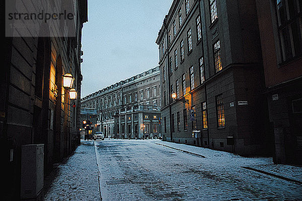 Schneebedeckte Straße inmitten von Gebäuden in der Stadt