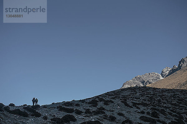 Menschen stehen auf Berg gegen klaren blauen Himmel