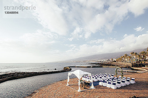 Hochwinkelansicht von Stühlen  die für die Hochzeitszeremonie auf dem Meer arrangiert wurden