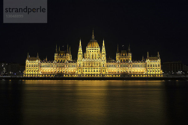 Beleuchtetes ungarisches Parlamentsgebäude an der Donau gegen den nächtlichen Himmel