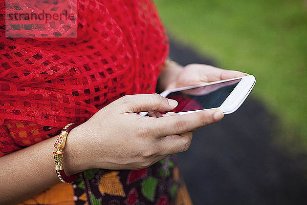 Ein Teil der Frau benutzt auf dem Feld ein Smartphone