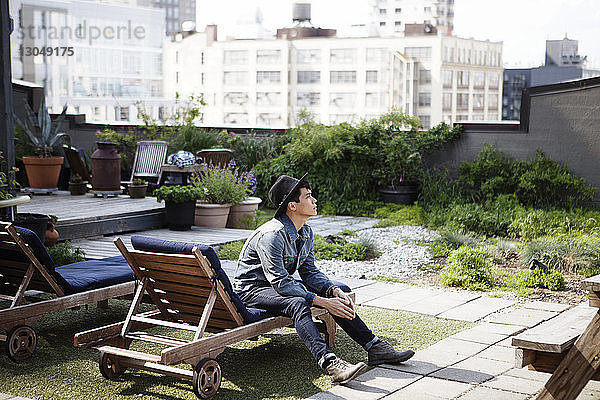 Nachdenklicher Mann sitzt auf einem Liegestuhl auf der Terrasse