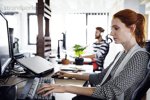 Seitenansicht einer Geschäftsfrau  die einen Computer im Kreativbüro benutzt