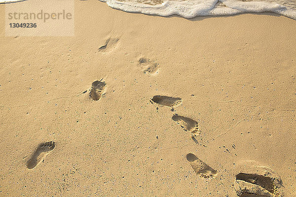 Hochwinkelansicht von Fußabdrücken auf Sand am Strand