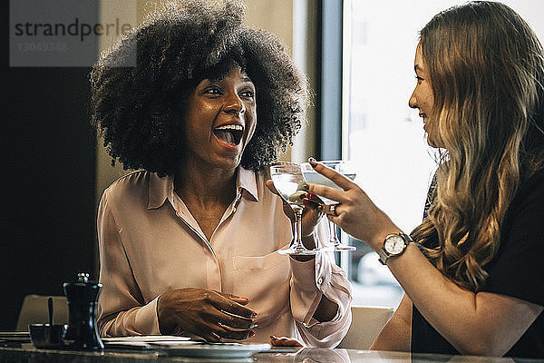 Fröhliche Geschäftsfrauen stoßen im Hotel auf Getränke an