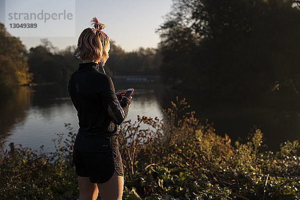 Frau mit Smartphone am See im Park