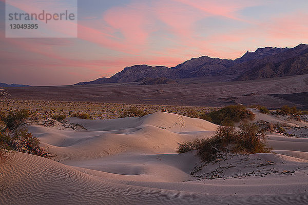 Majestätischer Blick auf Sanddünen vor Bergen und dramatischer Himmel im Death Valley National Park