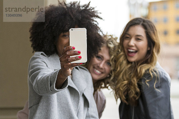 Fröhliche Geschäftsfrauen  die sich mit Smartphone selbstständig machen