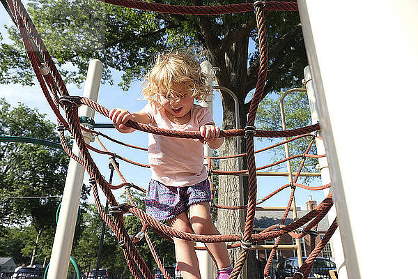 Sorgloses Mädchen klettert am Kletterseil in der Dschungelturnhalle auf dem Spielplatz