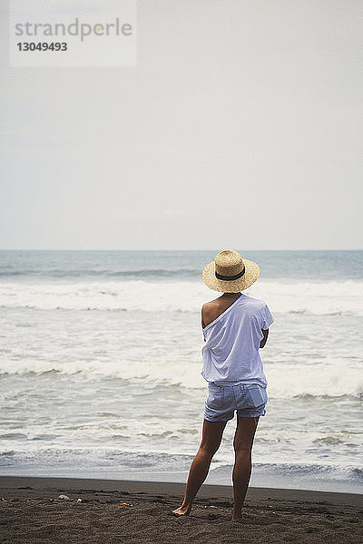 Rückansicht einer am Strand stehenden Frau vor klarem Himmel