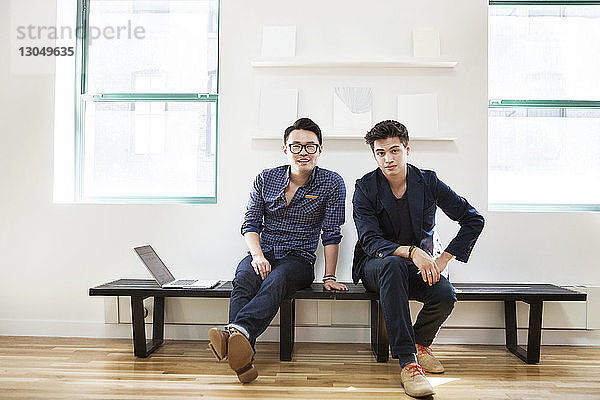 Porträt selbstbewusster Geschäftsleute auf der Bank sitzend in einem kreativen Büro