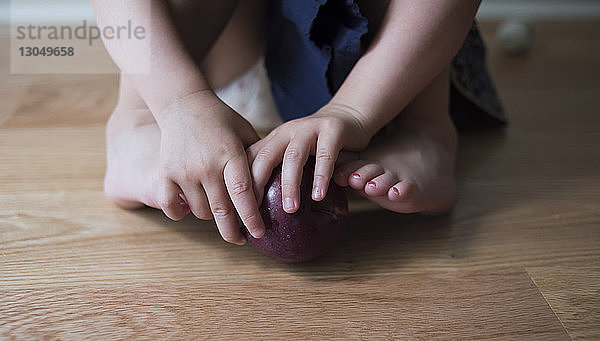 Unterer Teil des Mädchens spielt zu Hause mit dem Apfel