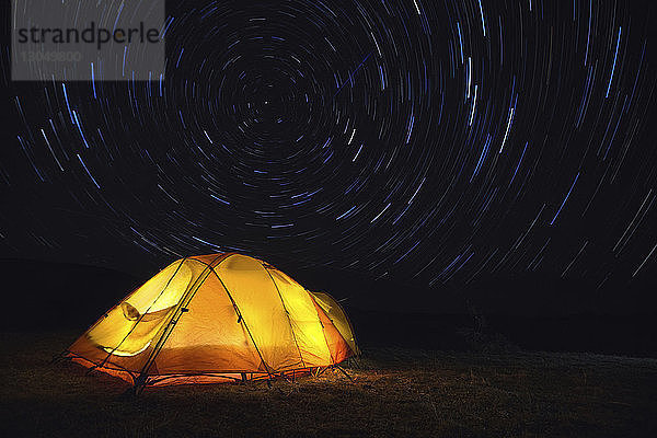 Szenische Ansicht der Sternenpfade über dem beleuchteten Zelt auf dem Feld