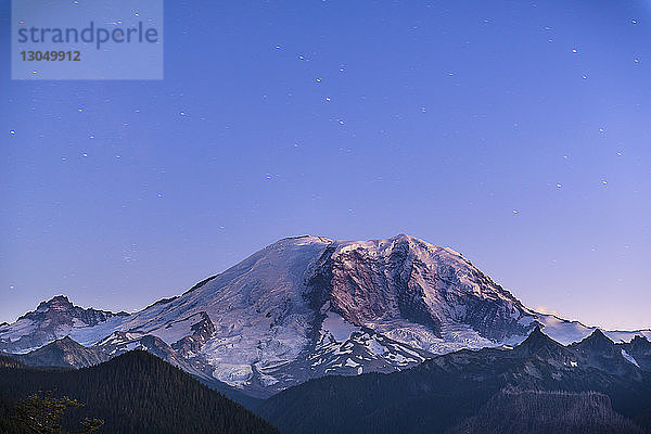 Szenenansicht eines schneebedeckten Berges vor blauem Himmel in der Abenddämmerung