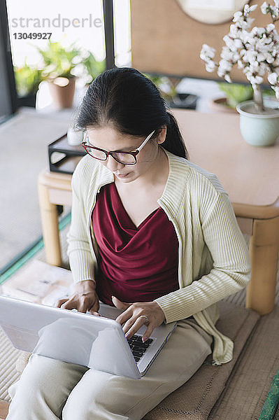 Frau benutzt Laptop-Computer  während sie zu Hause sitzt