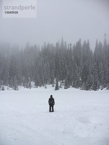 Rückansicht eines auf einem schneebedeckten Feld stehenden Mannes