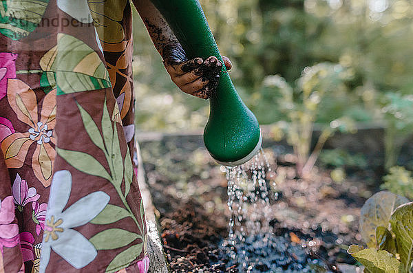 Beschnittenes Bild eines Mädchens  das Pflanzen im Garten gießt