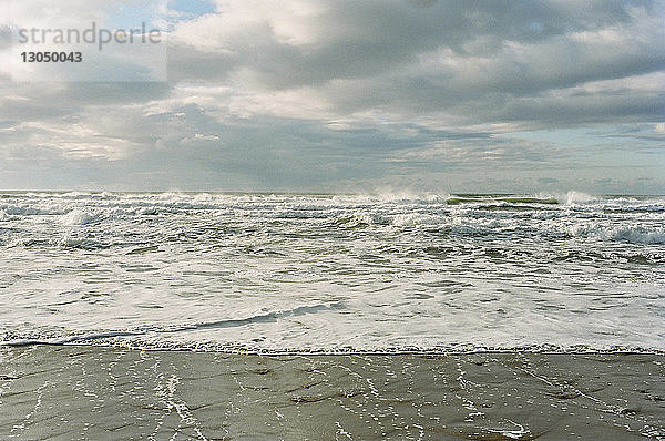 Szenische Ansicht von Wellen im Meer vor bewölktem Himmel