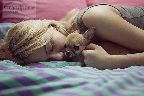 Teenager-Mädchen mit Chihuahua auf dem Bett liegend