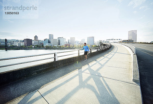 Mitteldistanz eines männlichen Athleten  der sich an einem sonnigen Tag auf einer Brücke streckt