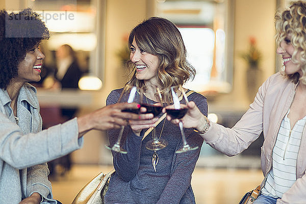 Fröhliche Geschäftsfrauen stoßen im Hotel auf Weingläser an