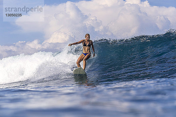 Frau surft im Meer gegen den Himmel