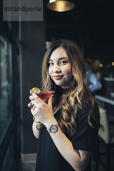 Porträt einer selbstbewussten Geschäftsfrau  die ein Getränk hält  während sie im Hotel steht