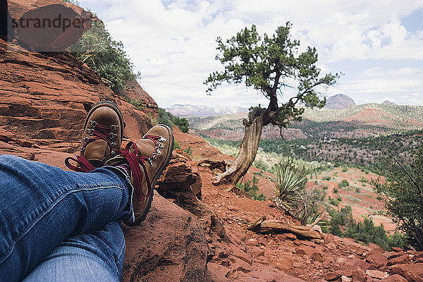 Niedriger Teil des Mannes sitzt auf einer Klippe am Grand Canyon