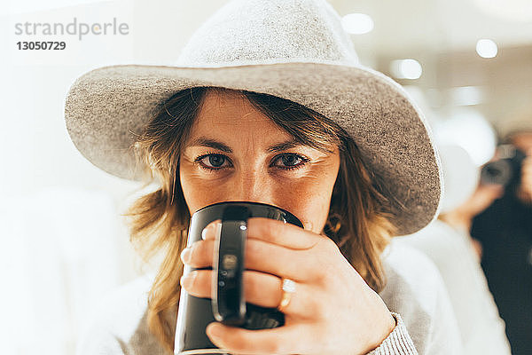 Porträt einer Geschäftsfrau mit Hut beim Kaffeetrinken im Hotel