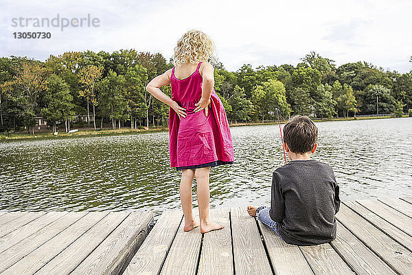 Mädchen mit Händen an der Hüfte sieht Freundin beim Angeln im See an