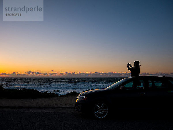 Silhouette eines Teenagers fotografiert  während er bei Sonnenuntergang im Sonnendach steht